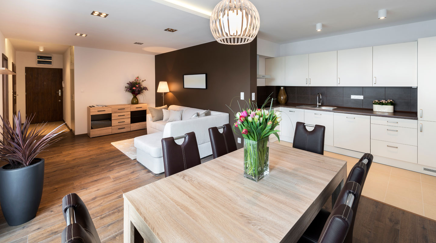 Gros plan sur des mains tenant des clés d'appartement avec un porte-clés en bois gravé, arrière-plan chaleureux flouté